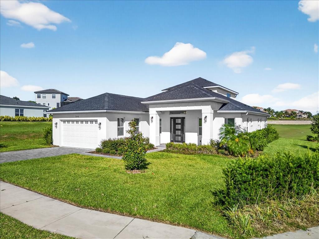 A white, single-story suburban house with a dark roof and a two-car garage — 200 SNOWY ORCHID WAY, LAKE ALFRED, FL