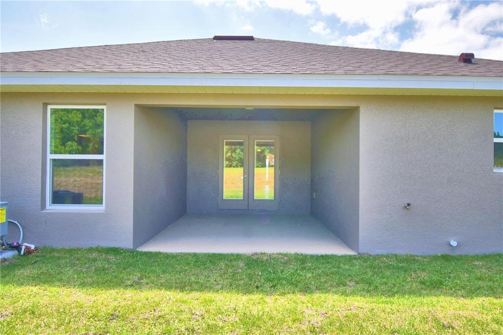 A covered concrete patio features double glass doors on the rear exterior of a house — 3644 LINDBERGH STREET, LAKELAND, FL