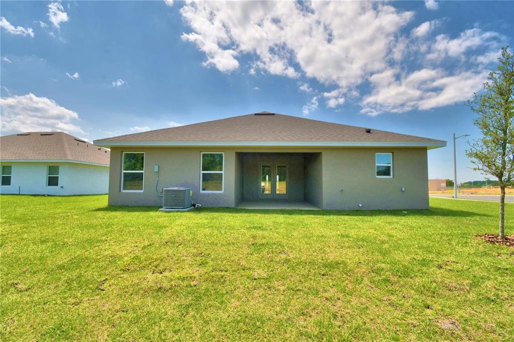 The rear exterior of a single-story house features a covered patio and a grassy yard — 3644 LINDBERGH STREET, LAKELAND, FL