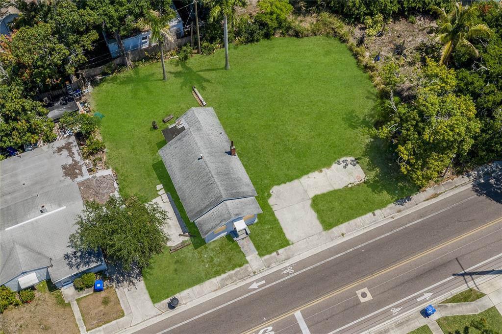 An aerial view shows a small house situated on a large, grassy corner lot — 15TH AVENUE S, ST PETERSBURG, FL