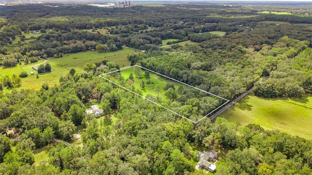 An aerial view shows a rectangular plot of land outlined in white amidst wooded surroundings — 20815 NW 62ND AVENUE, NEWBERRY, FL