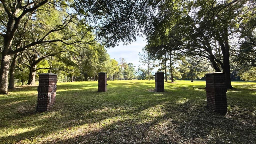 Four brick pillars stand in a grassy, tree-lined field under a bright sky — 20815 NW 62ND AVENUE, NEWBERRY, FL