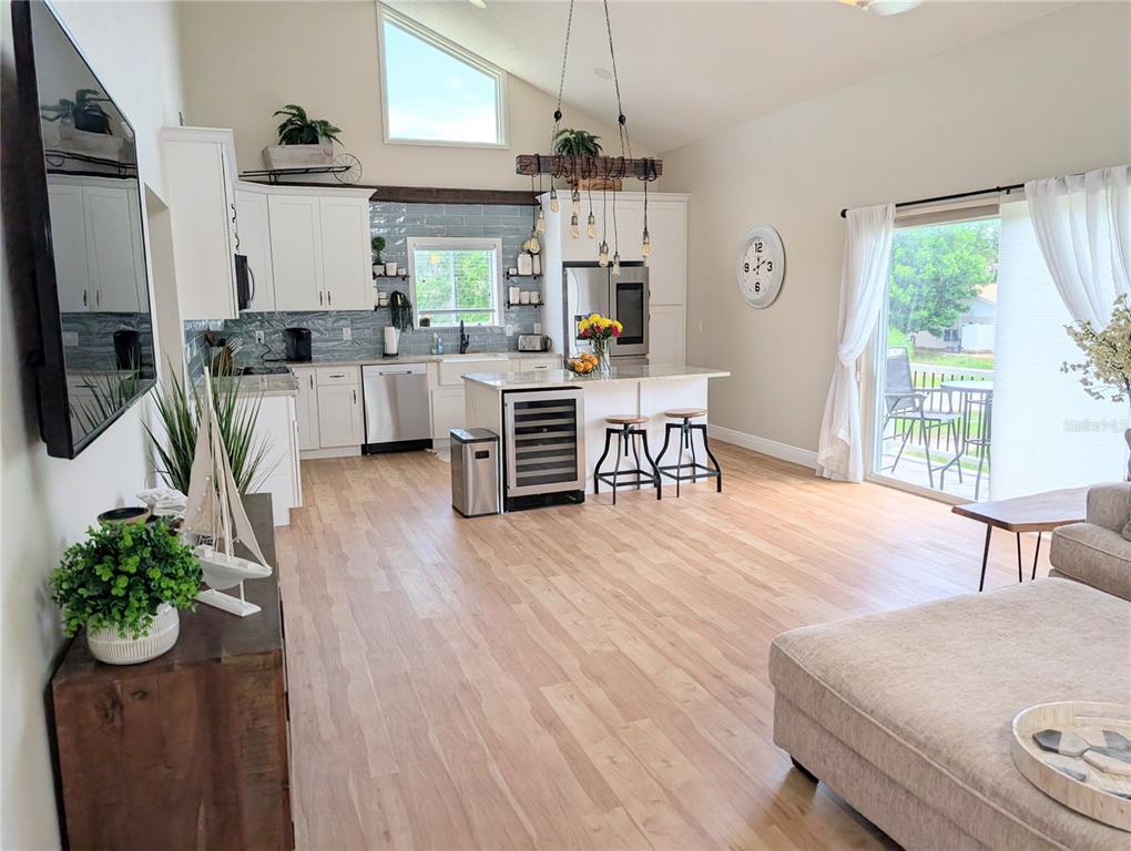 A bright, open-concept kitchen and living area features white cabinetry, light wood flooring, and vaulted ceilings — 2934 GULF OF MEXICO DRIVE UNIT 2934, LONGBOAT KEY, FL