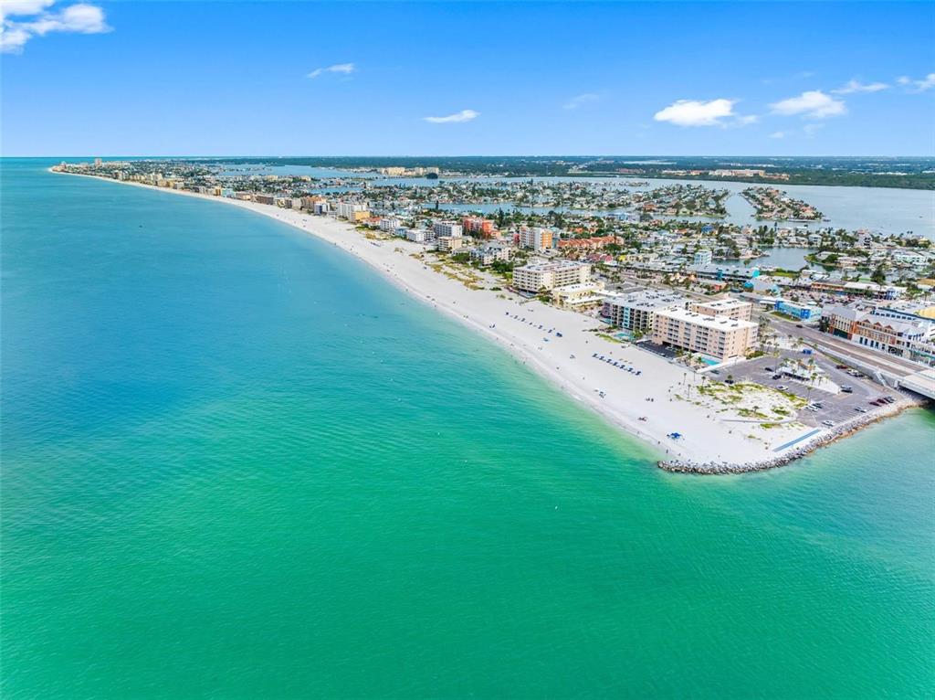An aerial view of a beach with hotels, a swimming pool, and a bridge nearby — 12924 GULF BOULEVARD UNIT 510, MADEIRA BEACH, FL