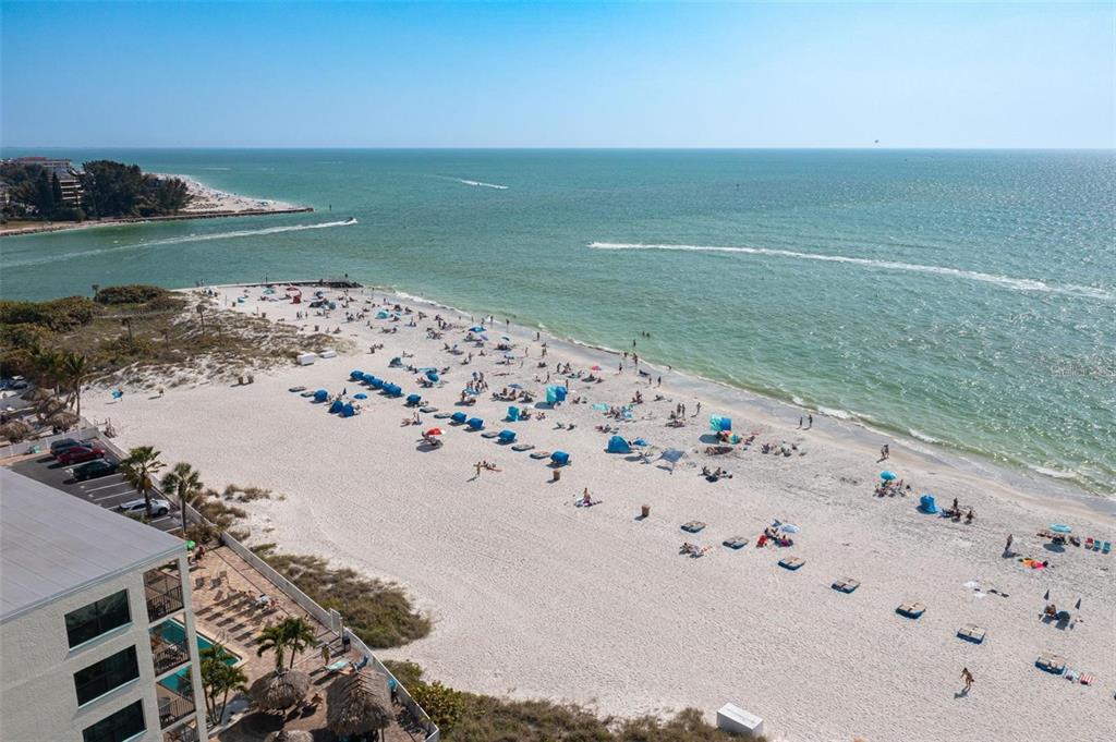 An aerial view shows a sandy beach along turquoise water with coastal buildings and homes — 12924 GULF BOULEVARD UNIT 510, MADEIRA BEACH, FL