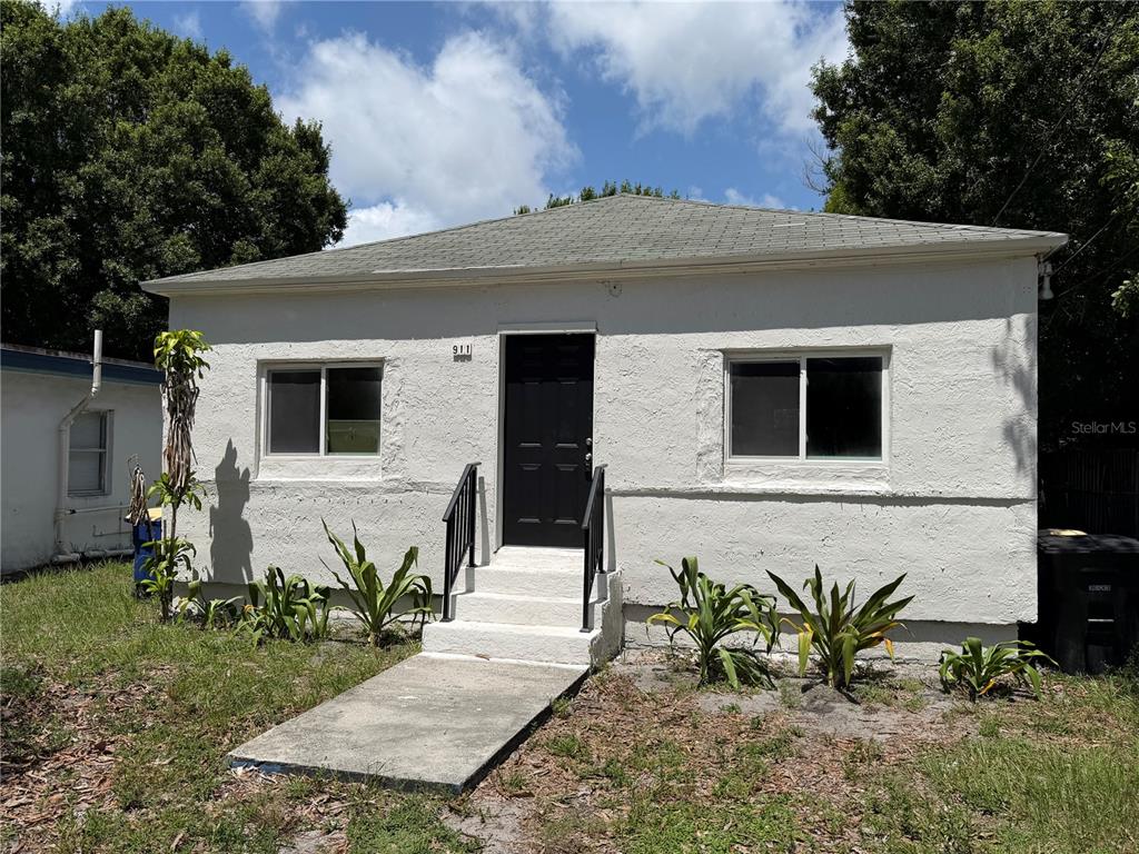 A small, white, single-story house with a black front door and a concrete walkway — 911 N 21ST STREET, FORT PIERCE, FL