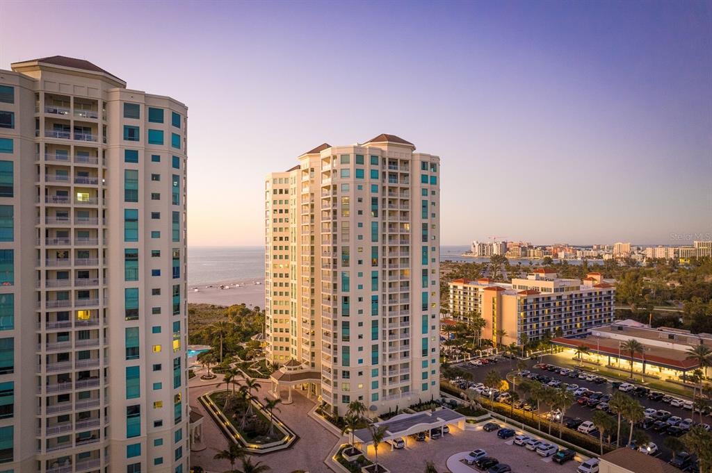 An aerial view shows two tall residential towers with swimming pools and landscaped grounds — 1170 SE GULF BOULEVARD UNIT 305, CLEARWATER BEACH, FL