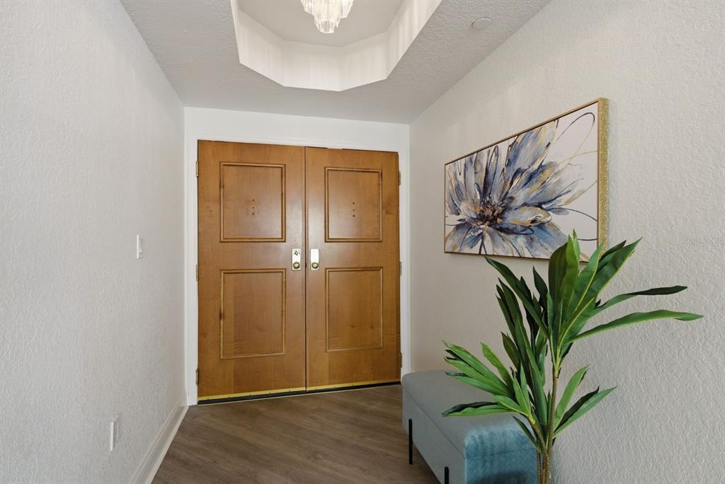 A living room features light wood-look flooring, a sofa, a console table, and balcony access — 1170 SE GULF BOULEVARD UNIT 305, CLEARWATER BEACH, FL