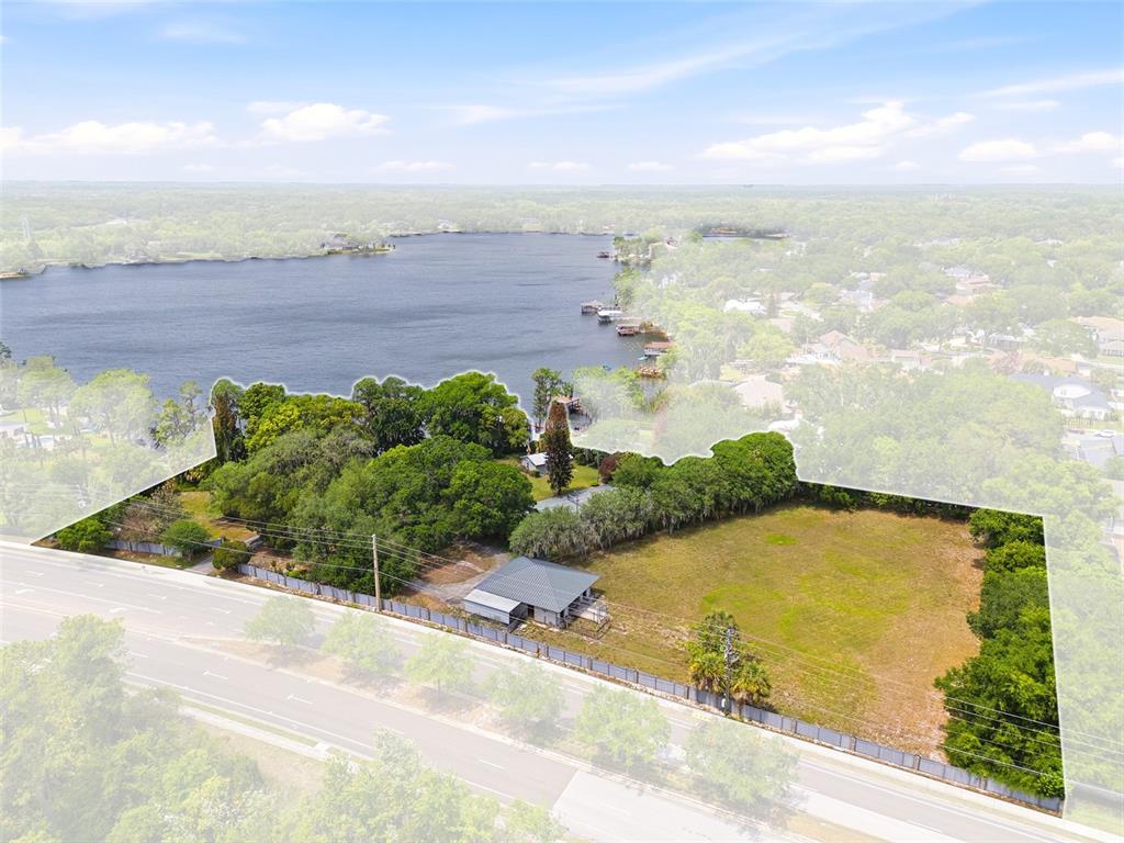 A brick house with large windows and a wooden walkway sits on a grassy lawn — 4910 E LAKE DRIVE, WINTER SPRINGS, FL