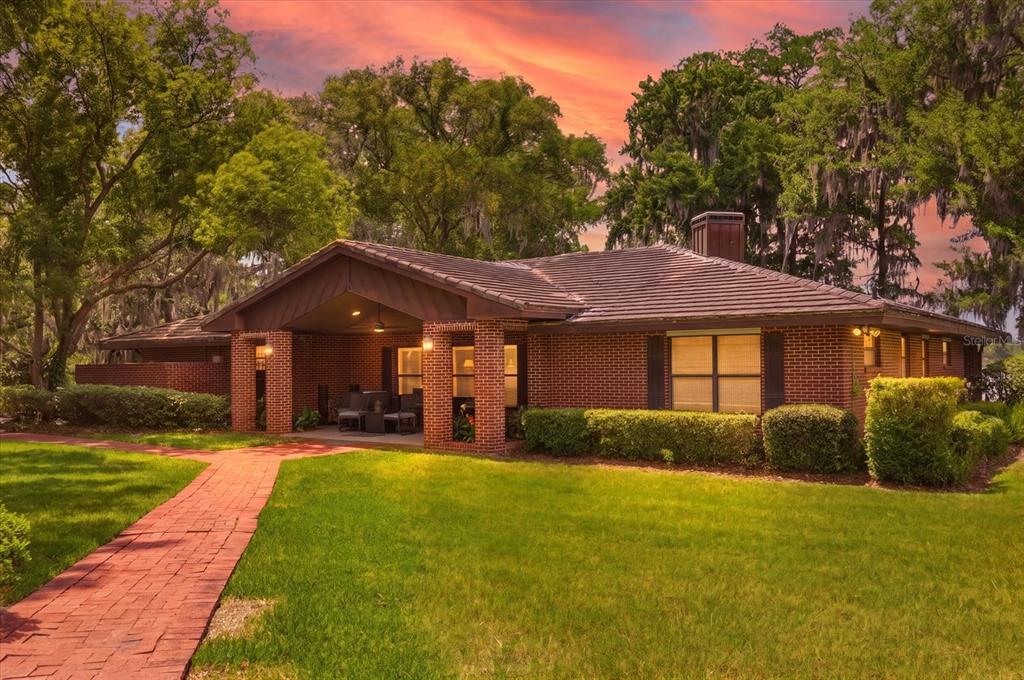 A wooden dock extends into a calm lake under a vibrant sunset sky — 4910 E LAKE DRIVE, WINTER SPRINGS, FL