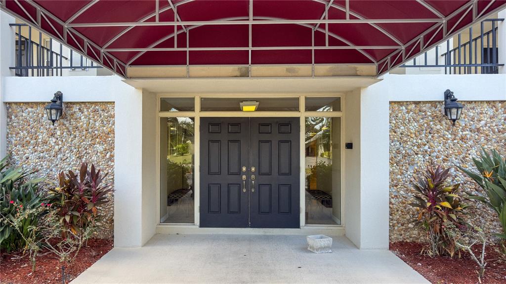 A double door entrance with a red awning and stone facade exterior — 7461 W COUNTRY CLUB DRIVE N UNIT 209, SARASOTA, FL