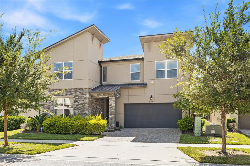 A two-story house with a stone facade, beige siding, and a two-car garage — 8975 AMELIA DOWNS TRAIL, KISSIMMEE, FL