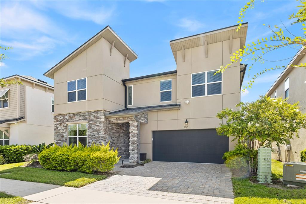 A two-story house with a stone facade, beige stucco, and a two-car garage — 8975 AMELIA DOWNS TRAIL, KISSIMMEE, FL