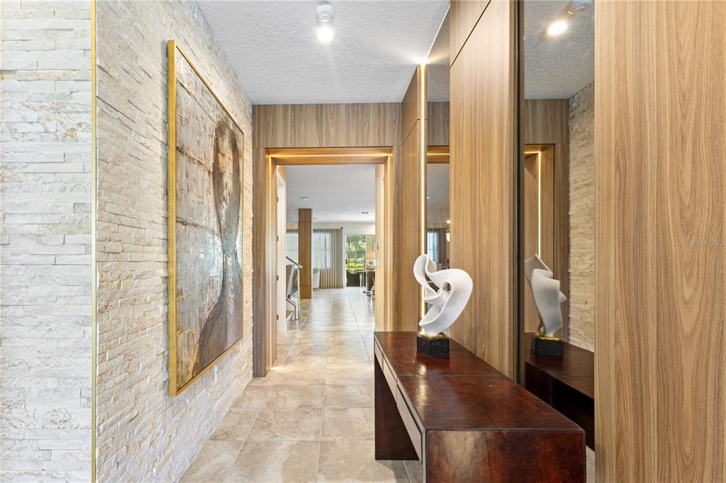 A hallway features stone walls, wood paneling, a console table with a sculpture, and recessed lighting — 8975 AMELIA DOWNS TRAIL, KISSIMMEE, FL