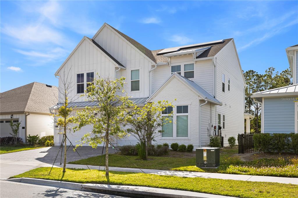 A two-story white house with a brick facade, a three-car garage, and a paved driveway — 6422 TRAILBLAZE BEND, ST CLOUD, FL