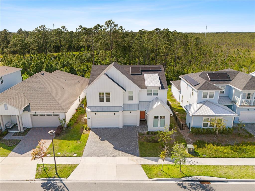 A two-story white house with a metal roof, vertical siding, and a paved driveway — 6422 TRAILBLAZE BEND, ST CLOUD, FL