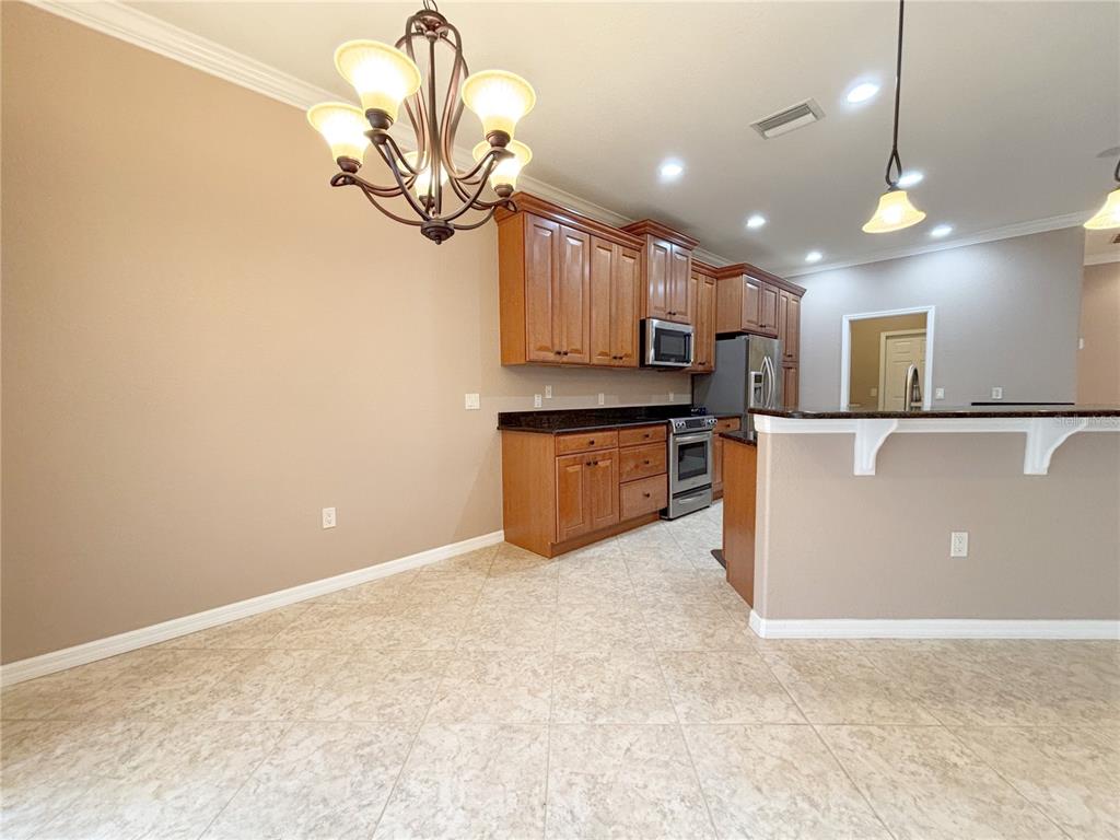 A kitchen features wood cabinets, dark countertops, tile flooring, and a dining area chandelier — 4577 BACK NINE DRIVE, WINTER HAVEN, FL