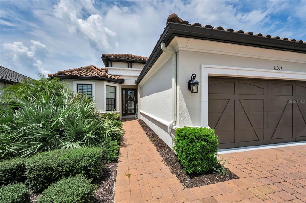 A paved walkway leads to the front entrance of a house with a brown garage — 11386 JUGLANS DRIVE, ODESSA, FL