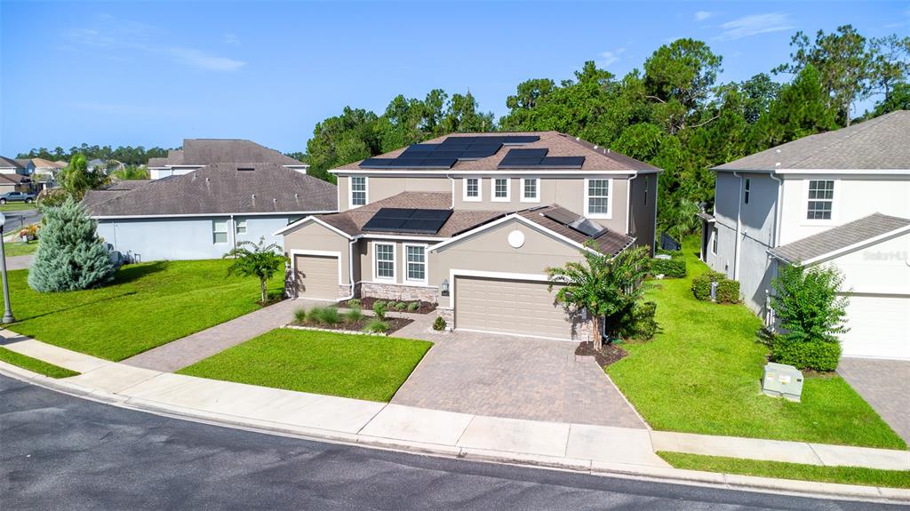 A two-story suburban house with a paved driveway, solar panels, and a grassy front yard — 491 BRUNSWICK DRIVE, DAVENPORT, FL