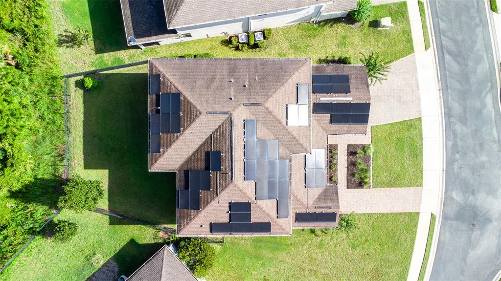 A two-story suburban house with a beige stucco exterior, solar panels, and a paved driveway — 491 BRUNSWICK DRIVE, DAVENPORT, FL