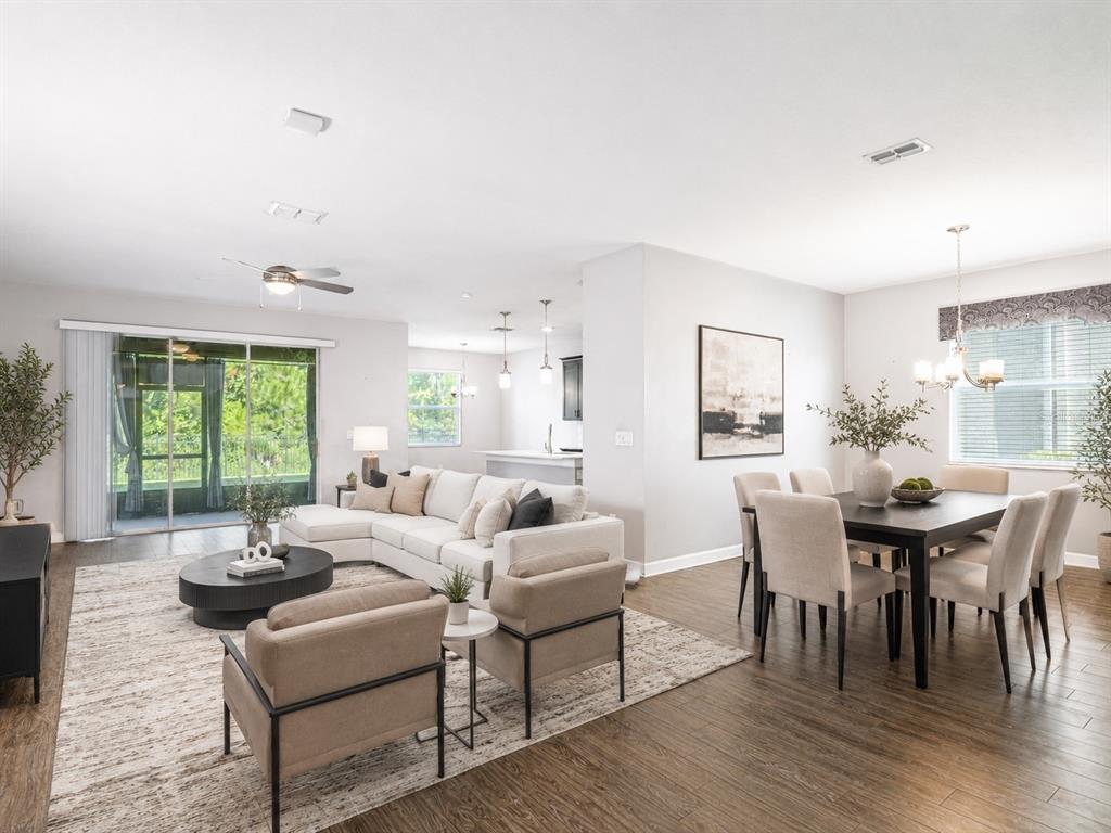 An open-concept living and dining area features wood-look tile flooring and a view of the kitchen — 491 BRUNSWICK DRIVE, DAVENPORT, FL