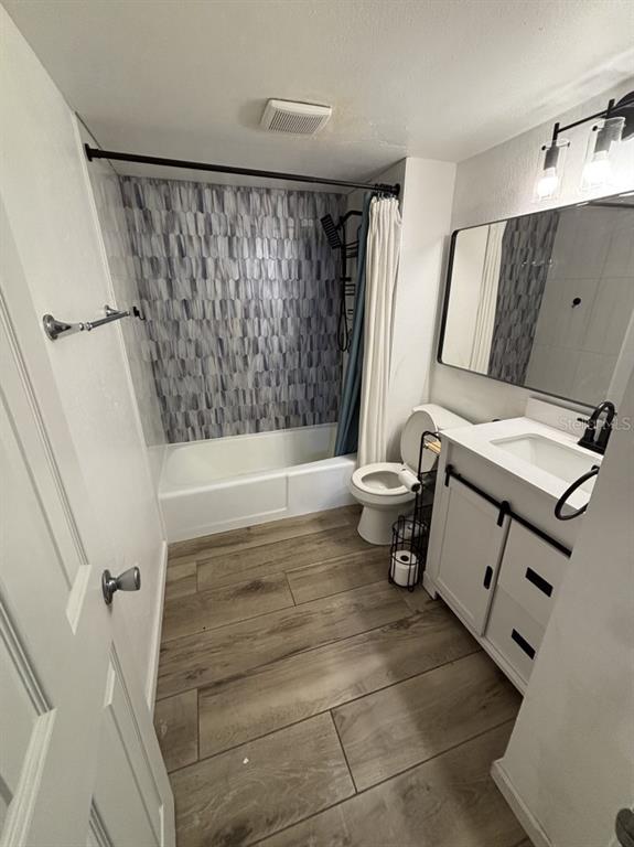 A bathroom features a tiled shower wall, wood-look flooring, a white vanity, and a toilet — 109 S OBRIEN STREET UNIT 123, TAMPA, FL