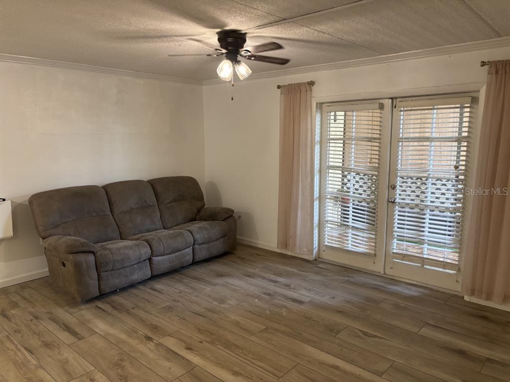 A living room features a brown reclining sofa, wood-look flooring, and glass-paned double doors — 109 S OBRIEN STREET UNIT 123, TAMPA, FL