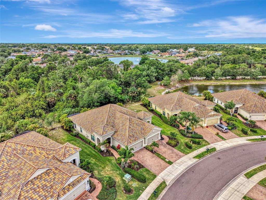 An aerial view of suburban houses with tile roofs near a lake and wooded area — 1321 BACKSPIN DRIVE, ENGLEWOOD, FL