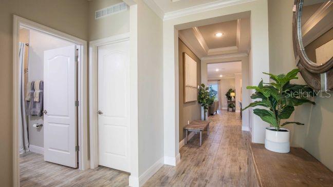 A hallway with wood-look tile flooring leads toward an open living area with two closed doors — 8646 OAKSTONE CIRCLE, LEESBURG, FL