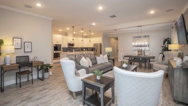 An open-concept living room, dining area, and kitchen with light wood floors and neutral walls — 8646 OAKSTONE CIRCLE, LEESBURG, FL
