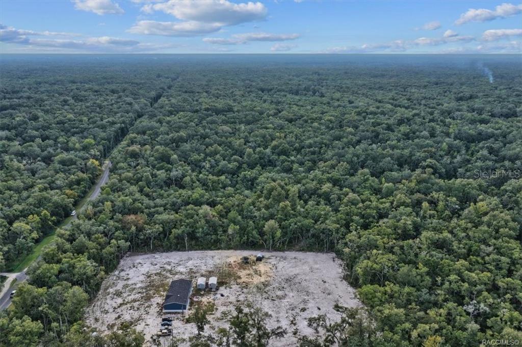 An aerial view shows a house on a cleared lot surrounded by dense forest — NE 206TH AVENUE, OLD TOWN, FL