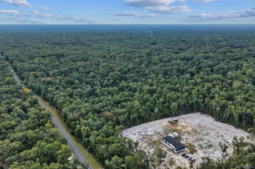 An aerial view shows a house on a cleared lot surrounded by dense forest — NE 206TH AVENUE, OLD TOWN, FL