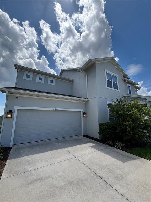 A two-story house with a light gray exterior, a two-car garage, and a concrete driveway — 13186 MAGNOLIA VALLEY DRIVE, CLERMONT, FL