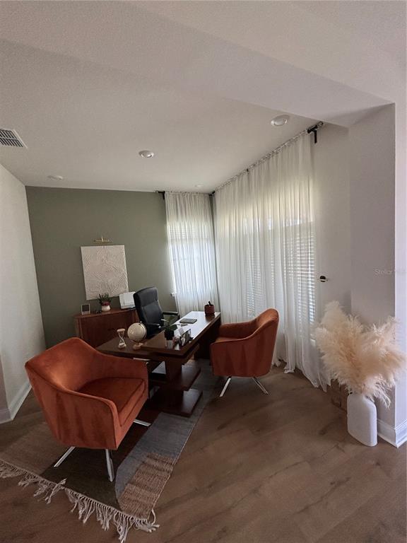 A home office features a wooden desk, two orange velvet chairs, and floor-to-ceiling white curtains — 13186 MAGNOLIA VALLEY DRIVE, CLERMONT, FL