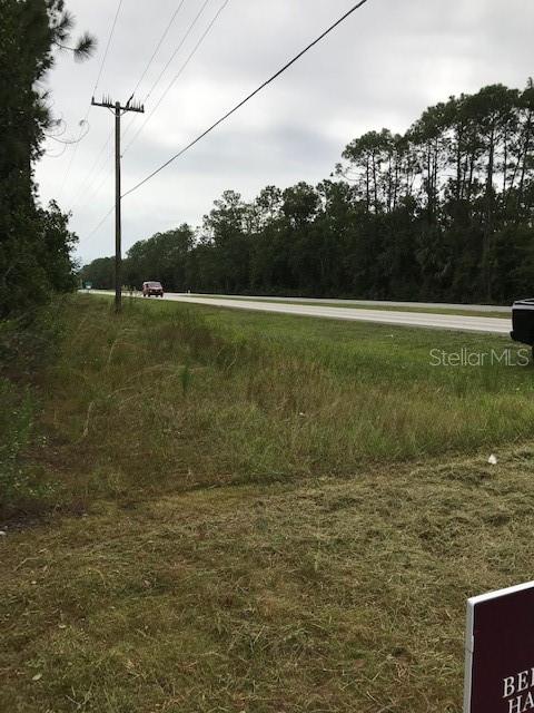 A grassy roadside lot with a utility pole and a view of a nearby highway — 2180 S US-1, BUNNELL, FL