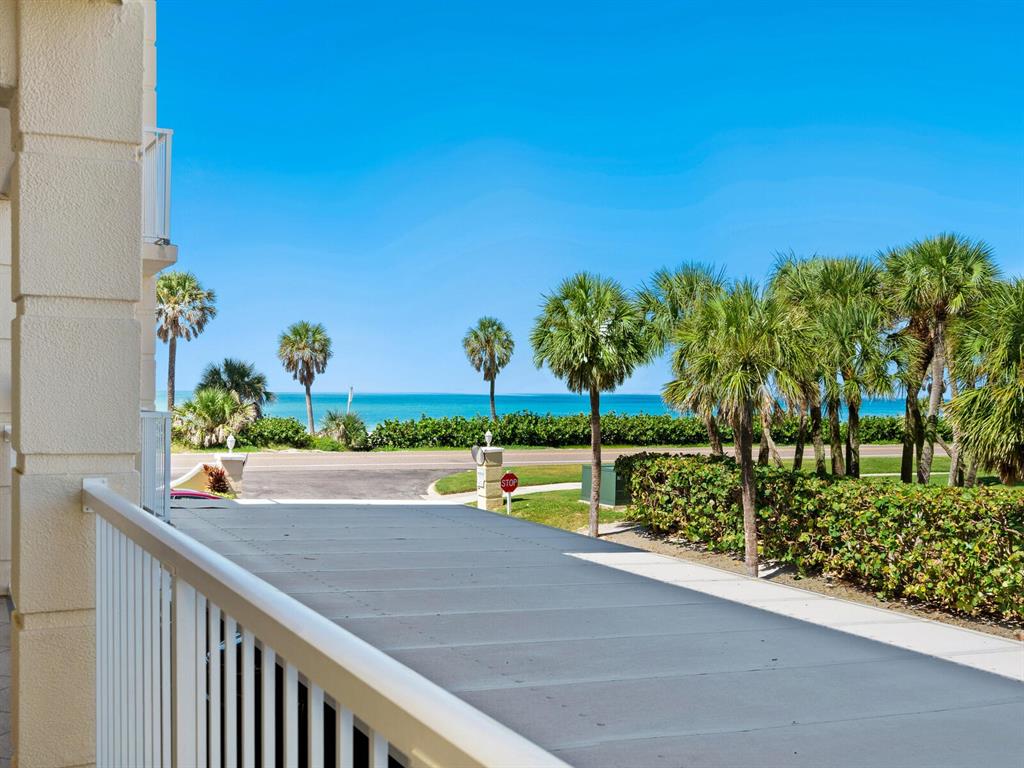 A view from a balcony overlooking a road, palm trees, and the ocean — 3802 GULF OF MEXICO DRIVE UNIT A203, LONGBOAT KEY, FL