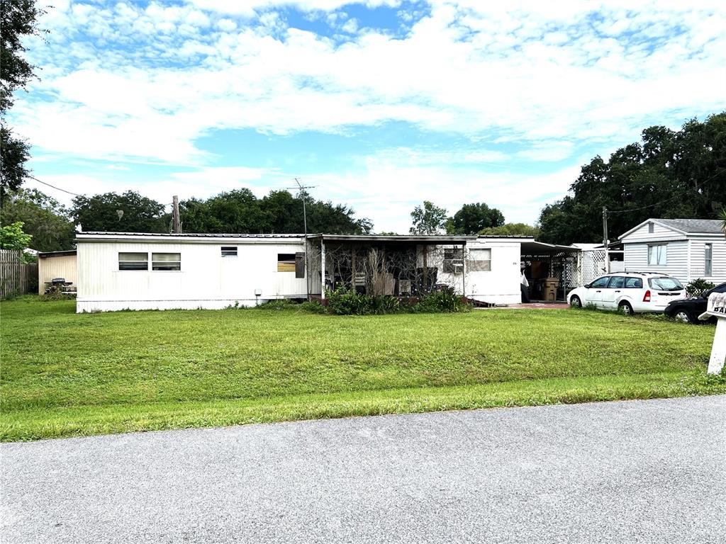 A single-story mobile home with a covered porch sits on a grassy lot — 170 N OAK DRIVE, KENANSVILLE, FL