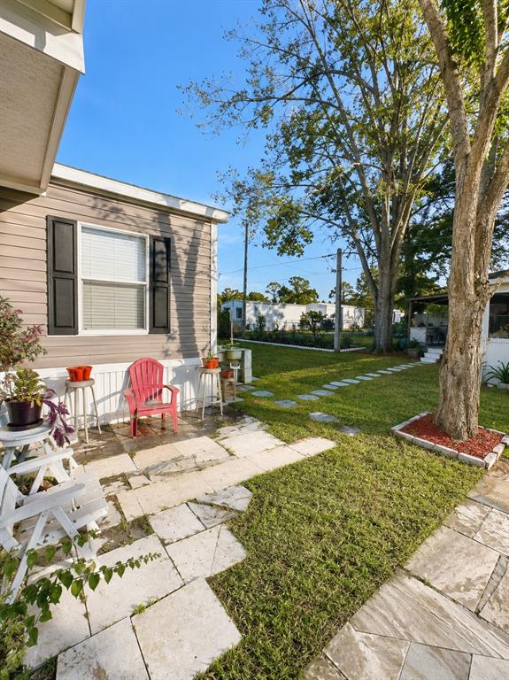 A side view of a mobile home with a stone patio and a grassy yard — 1111 AVENUE G, ORMOND BEACH, FL