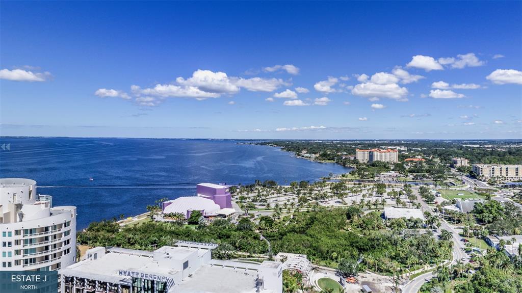 An aerial view shows a waterfront hotel, a purple performing arts center, and surrounding parkland — 555 QUAY COMMONS UNIT 1704, SARASOTA, FL