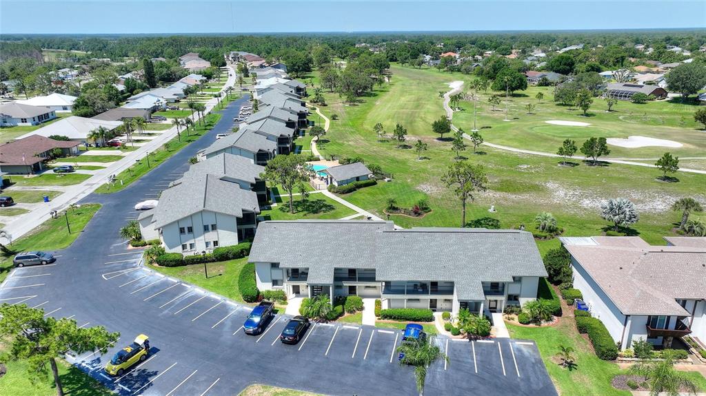 An aerial view shows multi-unit residential buildings with gray roofs situated next to a golf course — 3511 EDGEWATER DRIVE UNIT 3511, SEBRING, FL