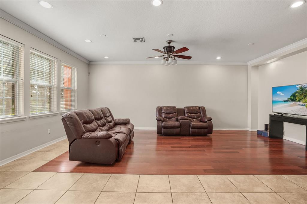 A living room with tile and wood flooring, two brown leather sofas, and a television — 561 TELFAIR SQUARE COURT, SANFORD, FL