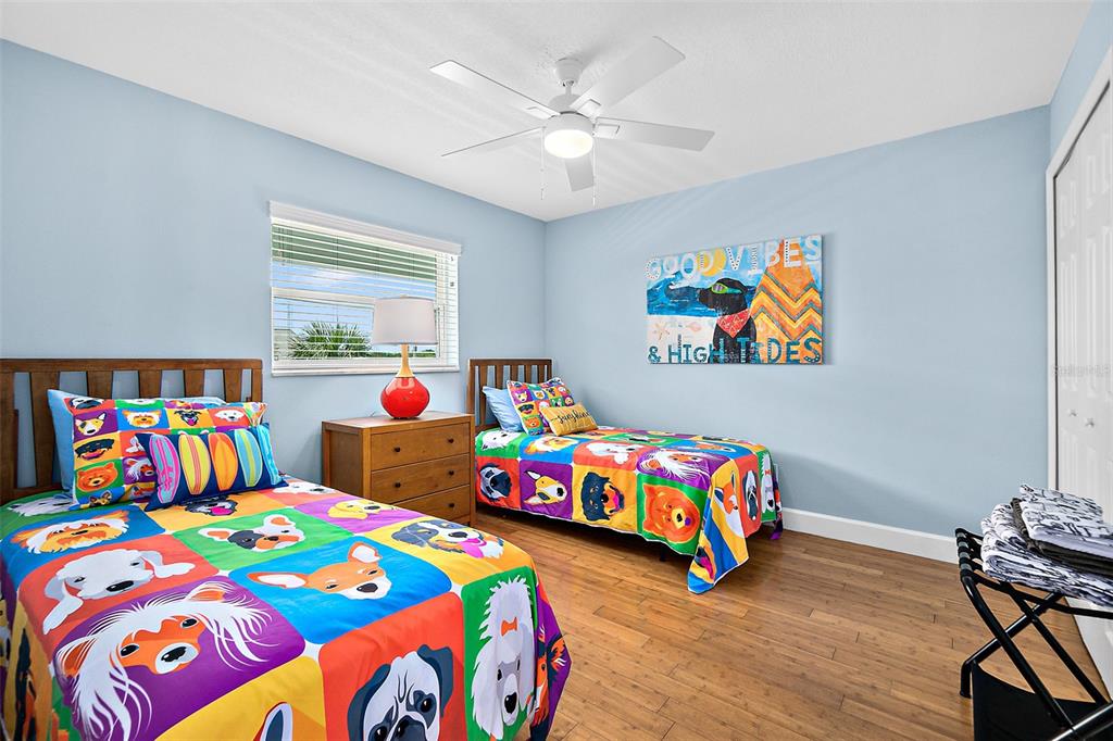 A bedroom features two twin beds with colorful dog-themed bedding and light blue walls — 300 S CENTRAL AVENUE UNIT 203, FLAGLER BEACH, FL