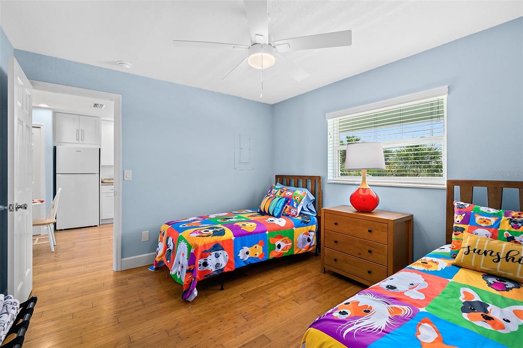 A bedroom with two twin beds, wood flooring, and a view into a kitchen — 300 S CENTRAL AVENUE UNIT 203, FLAGLER BEACH, FL