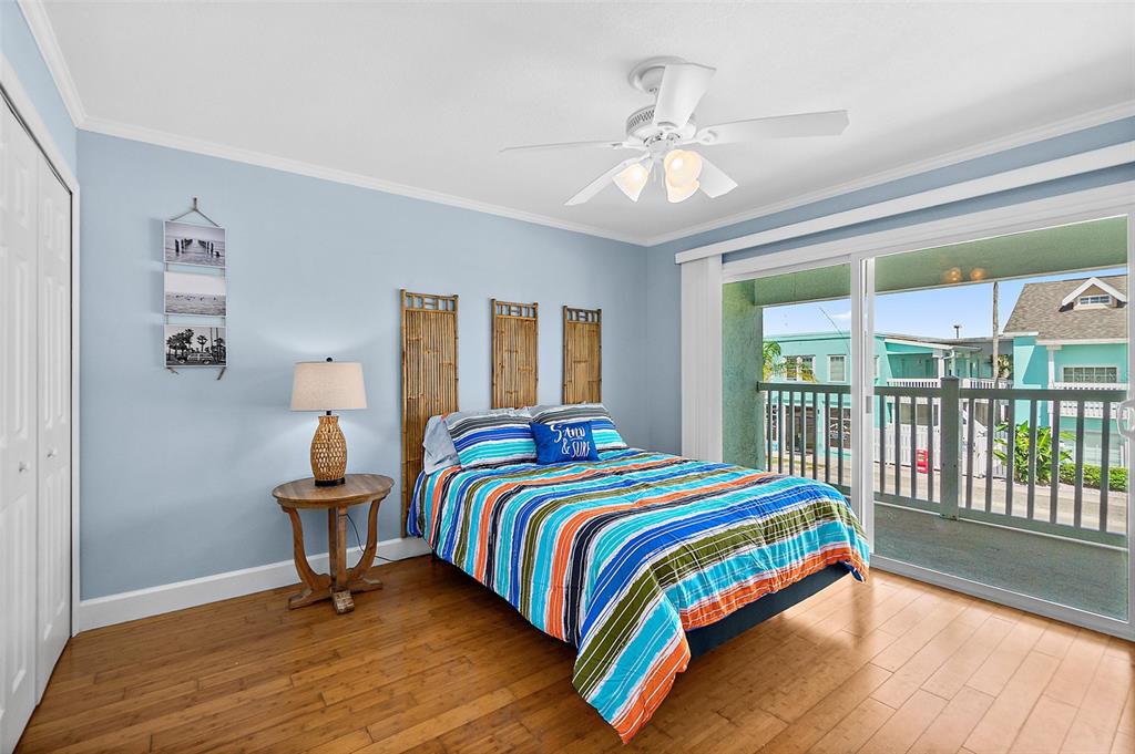 A bedroom with light blue walls, a striped bed, bamboo headboards, and a sliding glass door — 300 S CENTRAL AVENUE UNIT 203, FLAGLER BEACH, FL