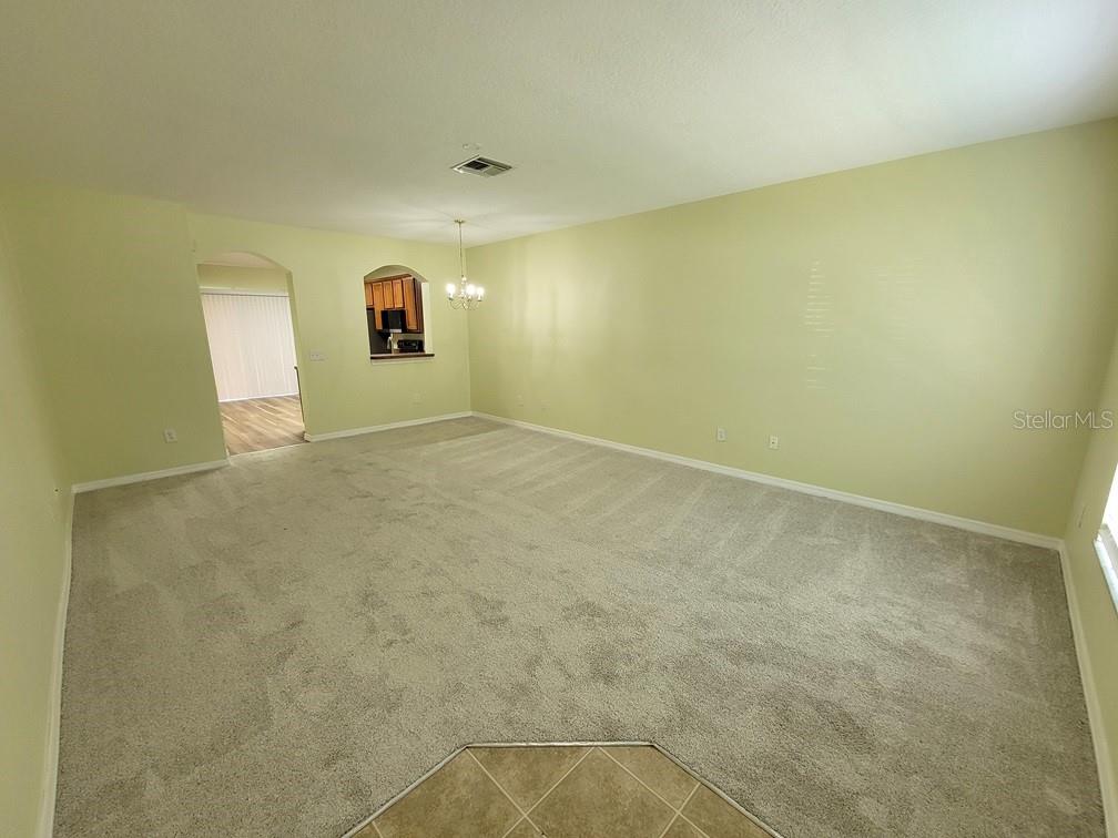 A spacious living room with light green walls, beige carpeting, and a dining area pass-through — 16414 SWAN VIEW CIRCLE, ODESSA, FL