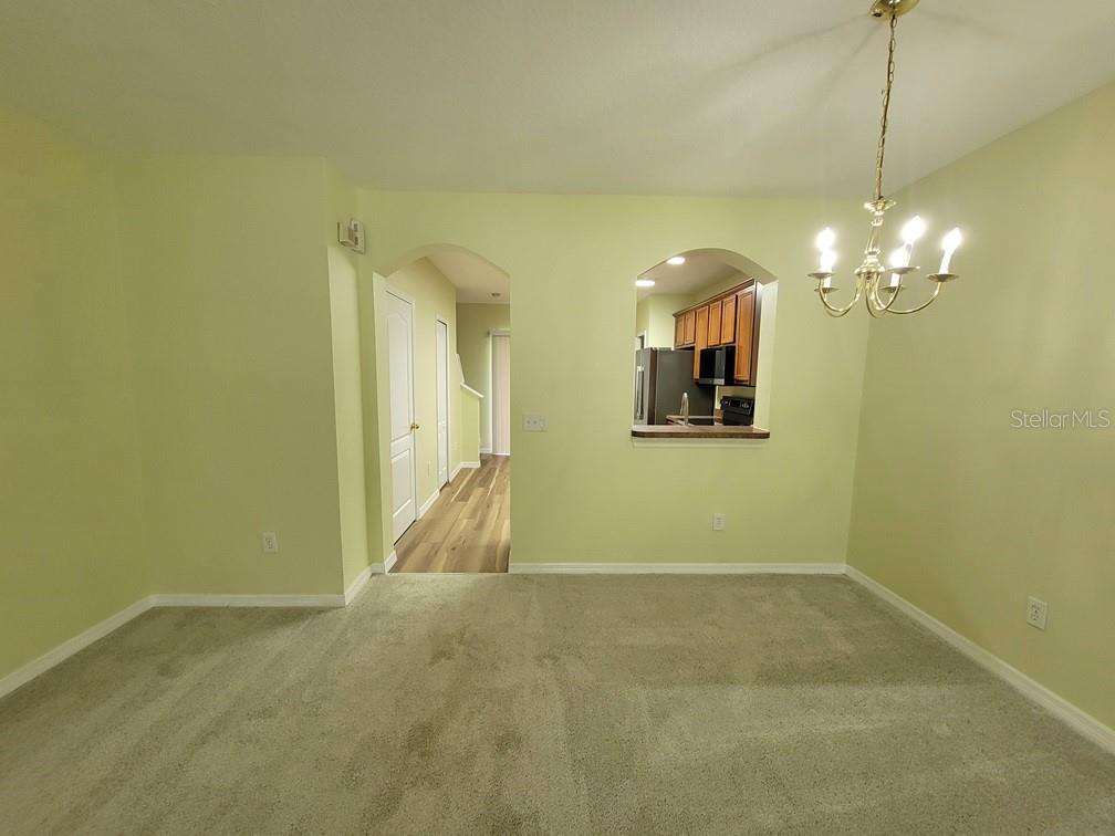 A dining area with beige carpet, light green walls, and a pass-through window to the kitchen — 16414 SWAN VIEW CIRCLE, ODESSA, FL