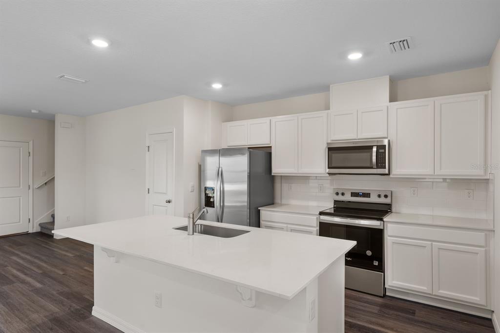 A modern kitchen features white cabinets, stainless steel appliances, and a large central island — 12086 SHINE VIEW LANE, WINTER GARDEN, FL