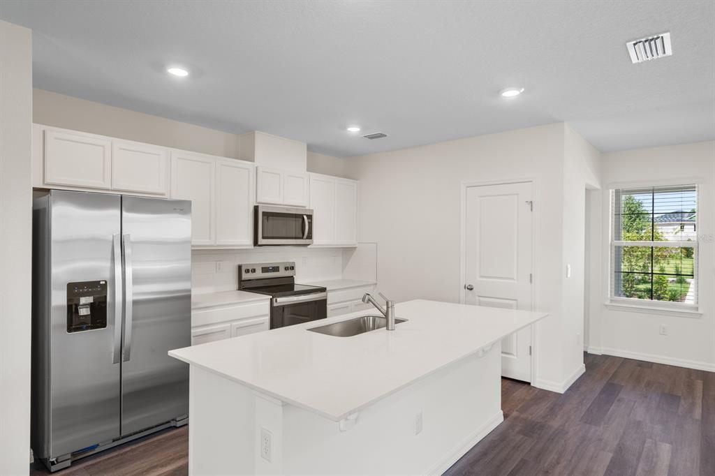 A kitchen with white cabinets, stainless steel appliances, a center island, and dark wood flooring — 12086 SHINE VIEW LANE, WINTER GARDEN, FL