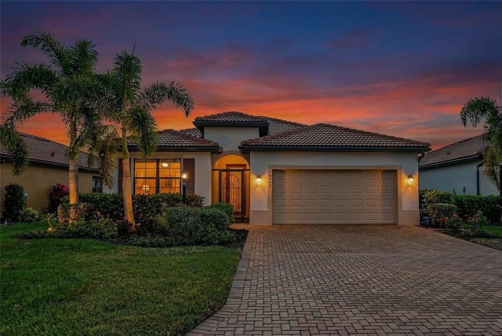 A single-story house with a tan stucco exterior, tile roof, and a two-car garage — 10202 MARBELLA DRIVE, BRADENTON, FL