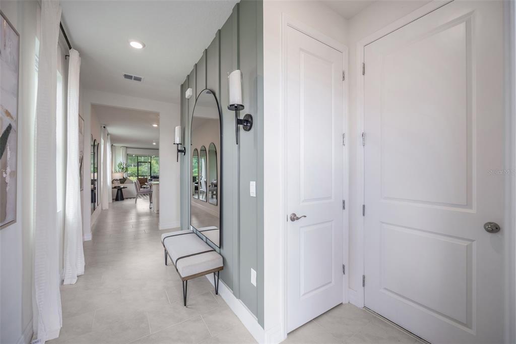 An entryway features a sage green accent wall, a tall arched mirror, and a bench — 3945 KENNEBUNK LOOP, MOUNT DORA, FL
